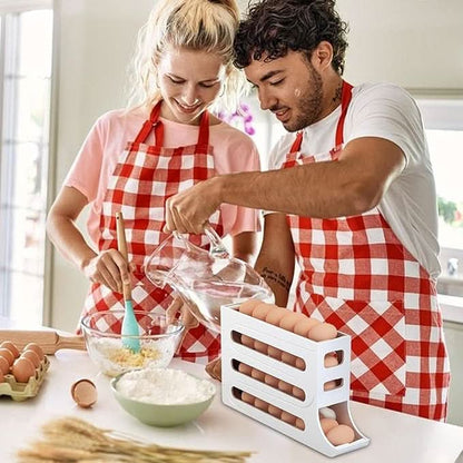 Couple wearing checkered aprons using an EggFlow Premium Refrigerator Egg Organizer in a kitchen